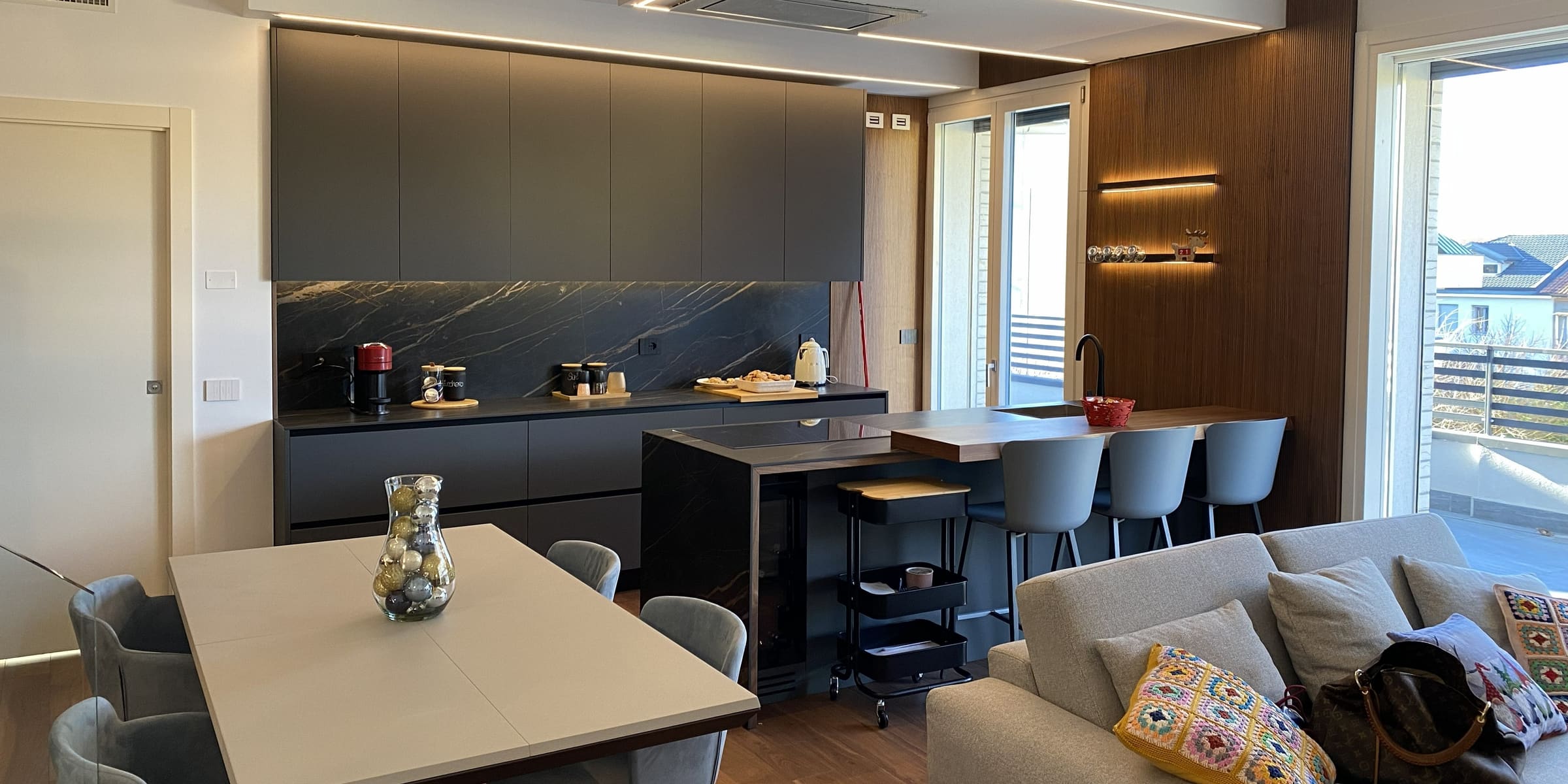 Cucina su misura con boiserie a doghe in legno, schienale in marmo e illuminazione LED integrata